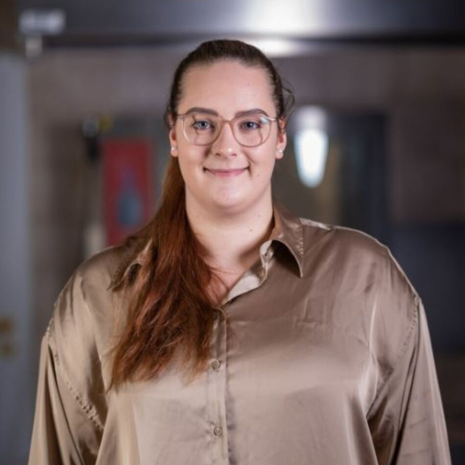 Vetrieb Eine Frau mit Brille und braunem Hemd.