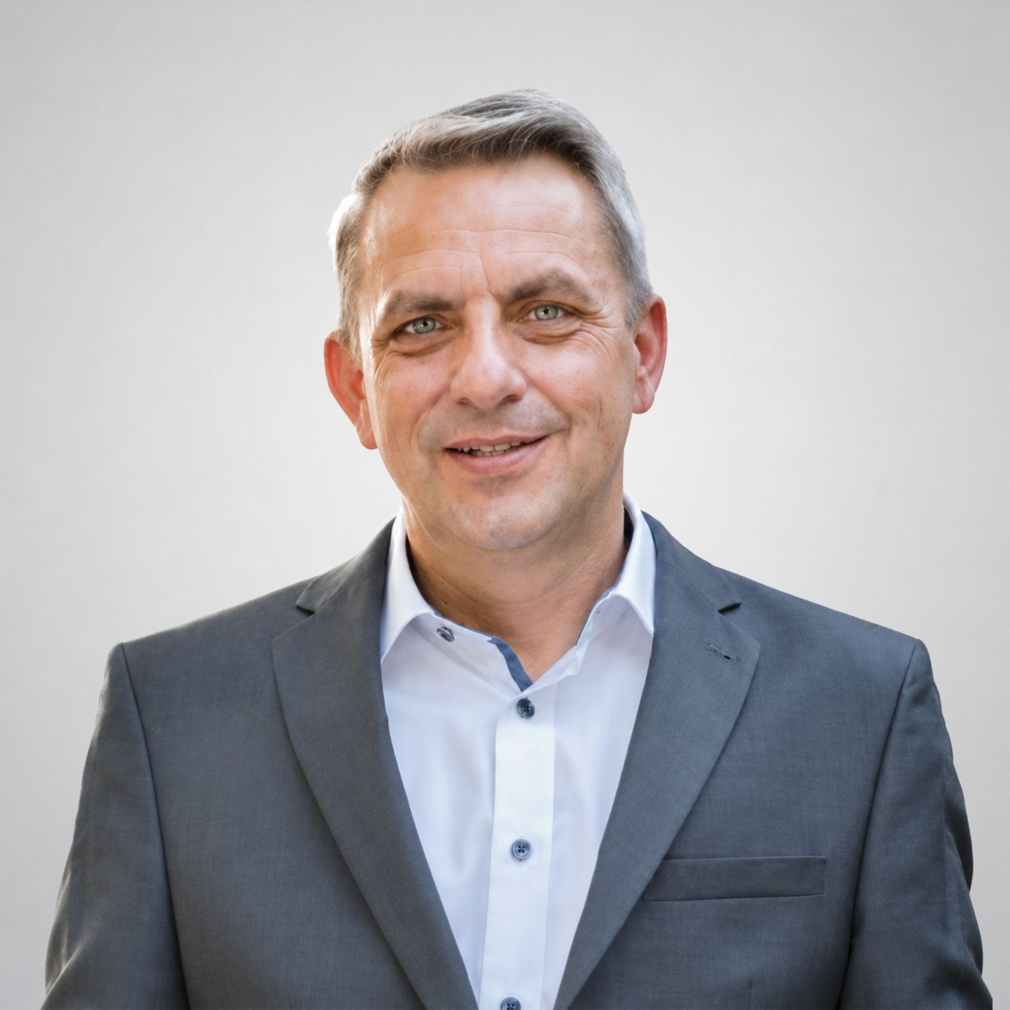 Ein Mann im Anzug lächelt.