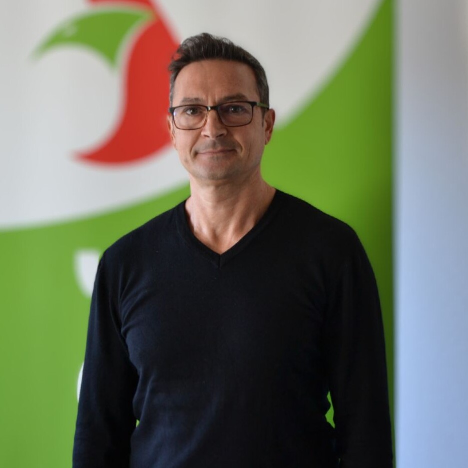 Ein Mann in einem schwarzen Hemd, lächelt.