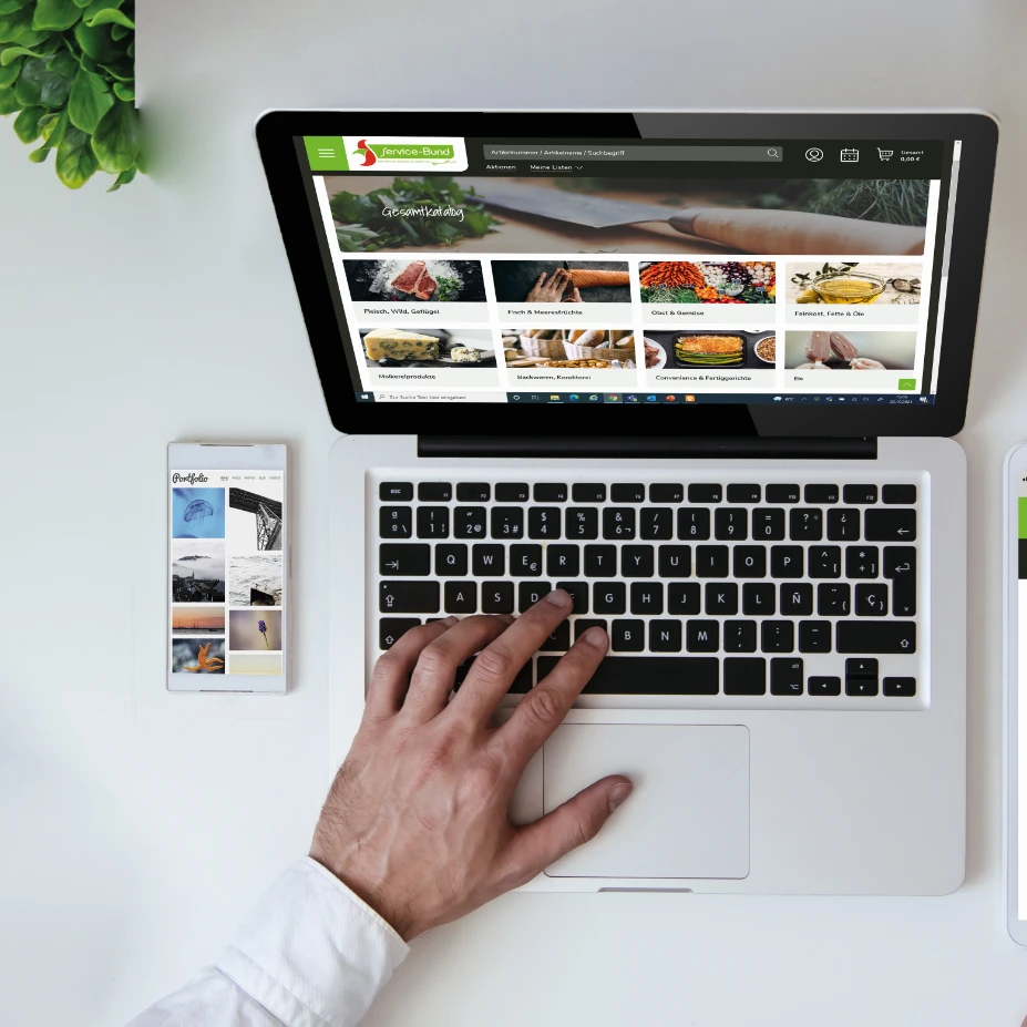 Eine Person benutzt einen Laptop und ein Telefon.