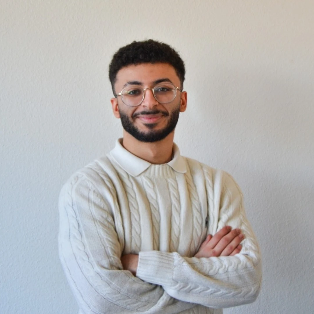 Ein Mann mit Brille und Bart trägt einen weißen Pullover.